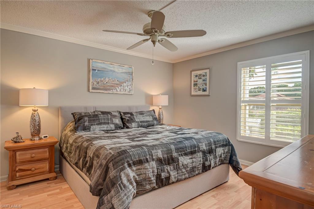 Bedroom featuring crown molding, a textured ceiling, ceiling fan, and light wood-type flooring