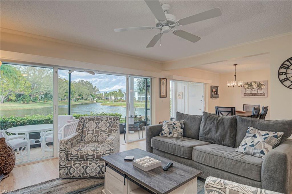 Living room with a water view, wood finished floors, crown molding, a chandelier, and a ceiling fan
