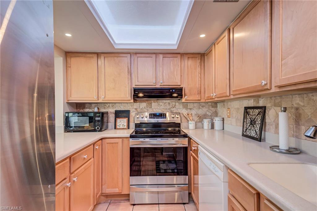 Kitchen featuring stainless steel appliances, light brown cabinetry, under cabinet range hood, recessed lighting, and tasteful backsplash