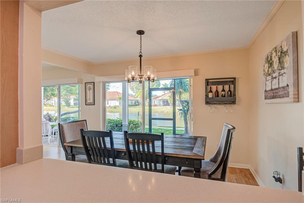 Dining room featuring wood finished floors, a chandelier, healthy amount of natural light, crown molding, and a water view
