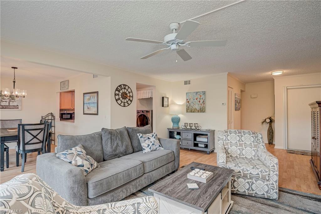 Living area featuring washer / clothes dryer, light wood-type flooring, a textured ceiling, a chandelier, and a ceiling fan