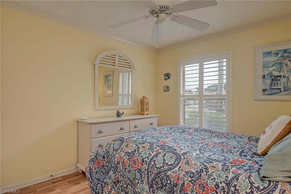 Bedroom featuring light wood-style floors, ornamental molding, ceiling fan, and a textured ceiling