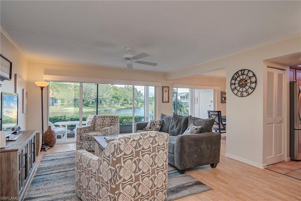 Living area with a water view, light wood-type flooring, a ceiling fan, and ornamental molding
