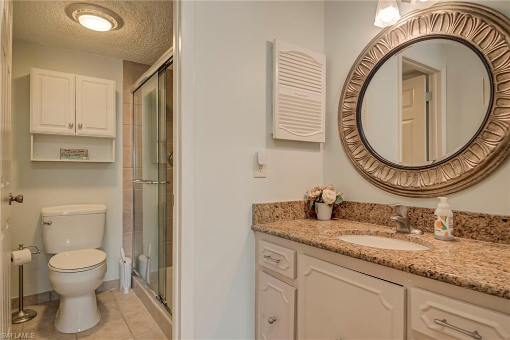 Bathroom featuring vanity, a stall shower, a textured ceiling, and light tile patterned flooring