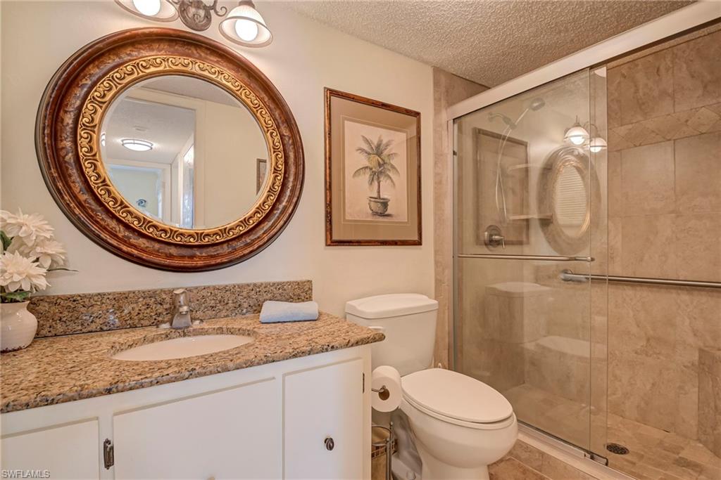Full bath featuring a textured ceiling, vanity, and a stall shower