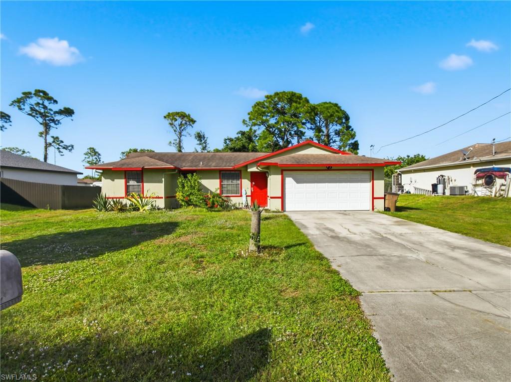 Ranch-style home featuring driveway, stucco siding, a front lawn, and an attached garage