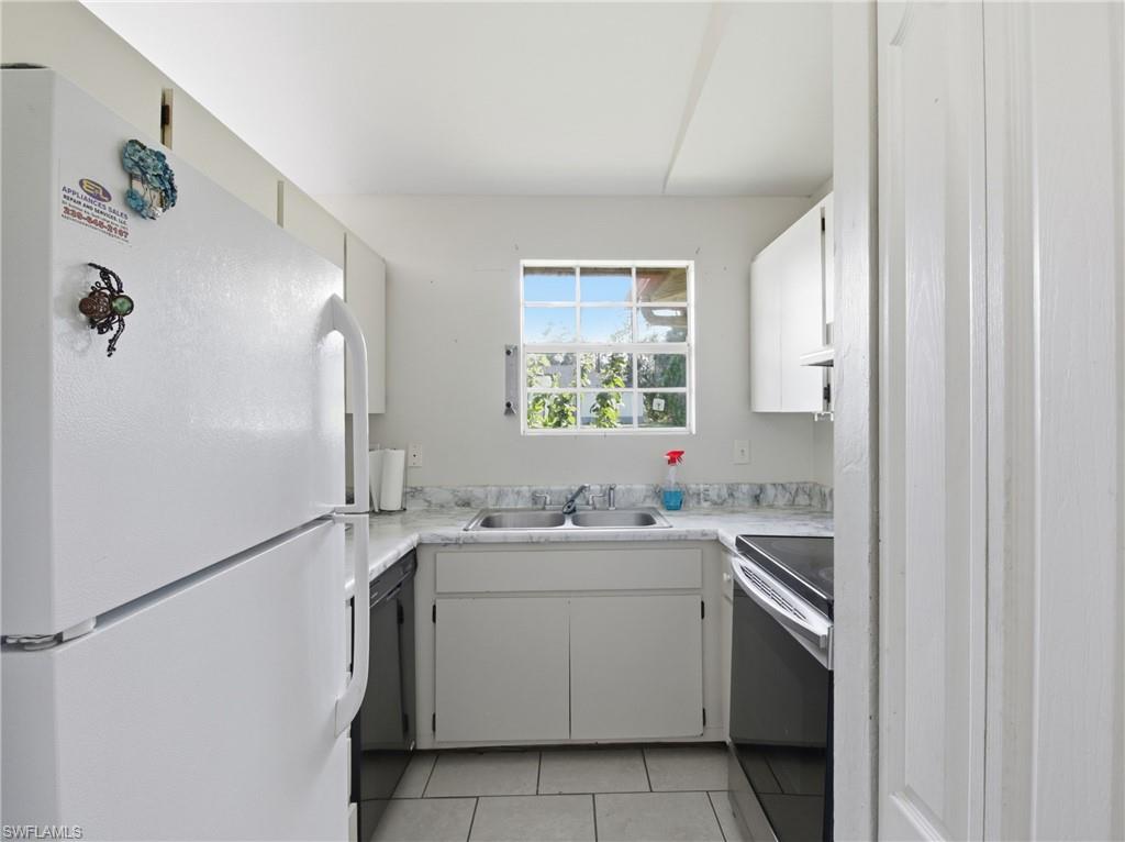 Kitchen with freestanding refrigerator, electric stove, light countertops, light tile patterned floors, and dishwasher