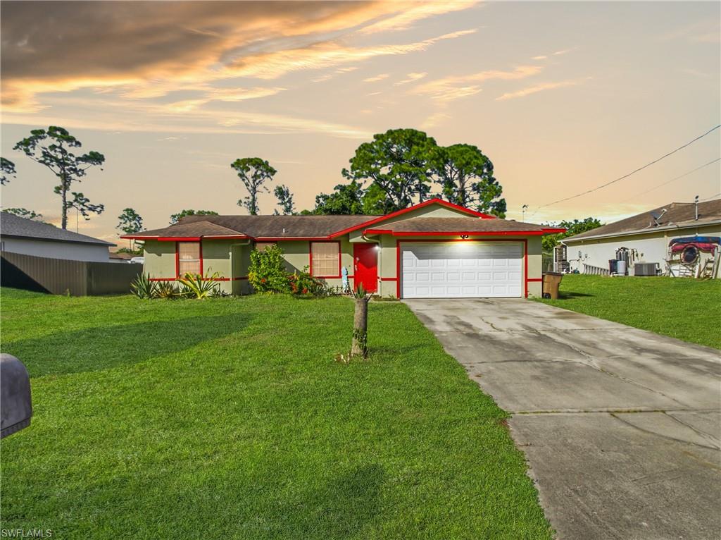 Ranch-style house featuring concrete driveway, a yard, and an attached garage