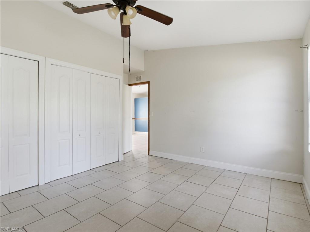 Unfurnished bedroom featuring two closets, a ceiling fan, vaulted ceiling, and light tile patterned floors