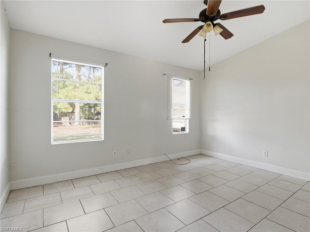 Empty room featuring healthy amount of natural light, a ceiling fan, light tile patterned floors, and vaulted ceiling