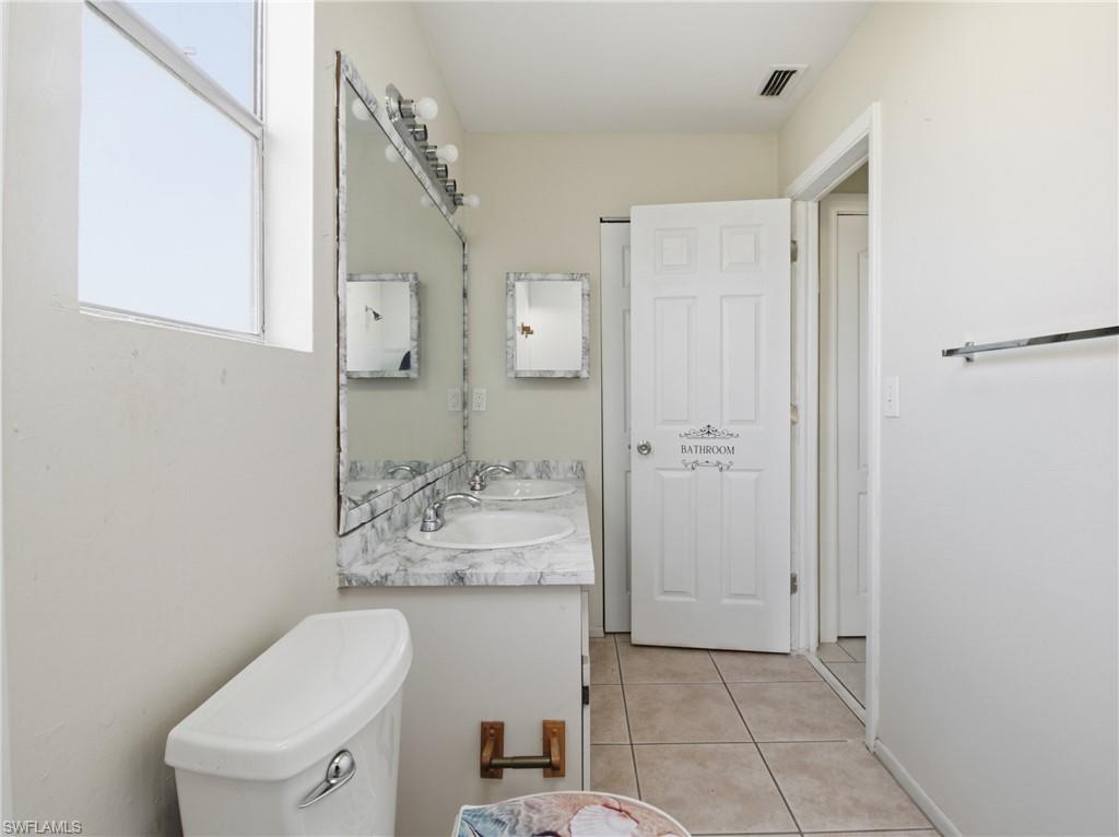 Bathroom with double vanity and light tile patterned floors