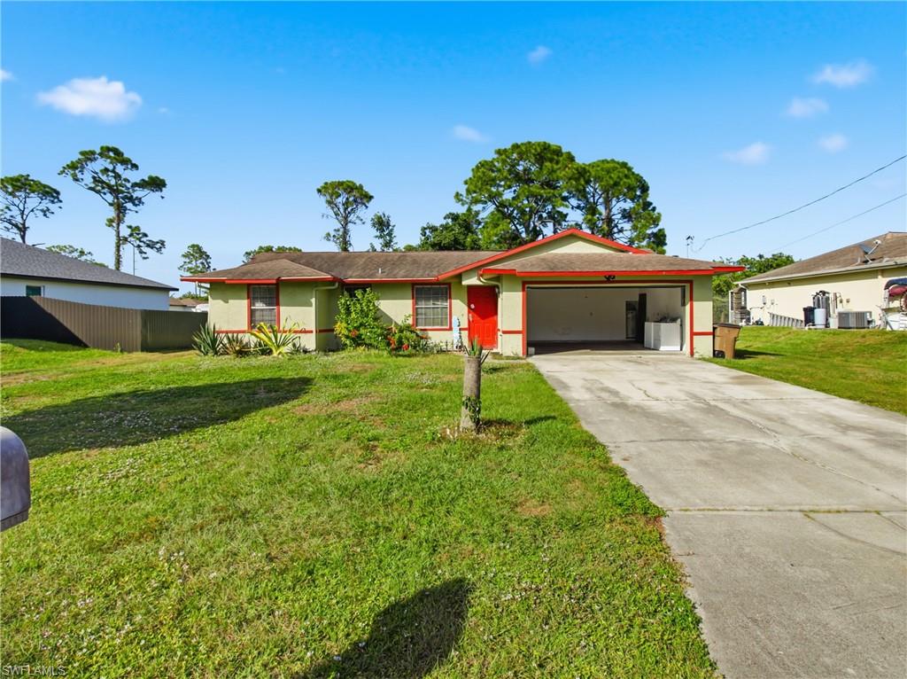 Ranch-style house with driveway, a front lawn, a garage, and stucco siding
