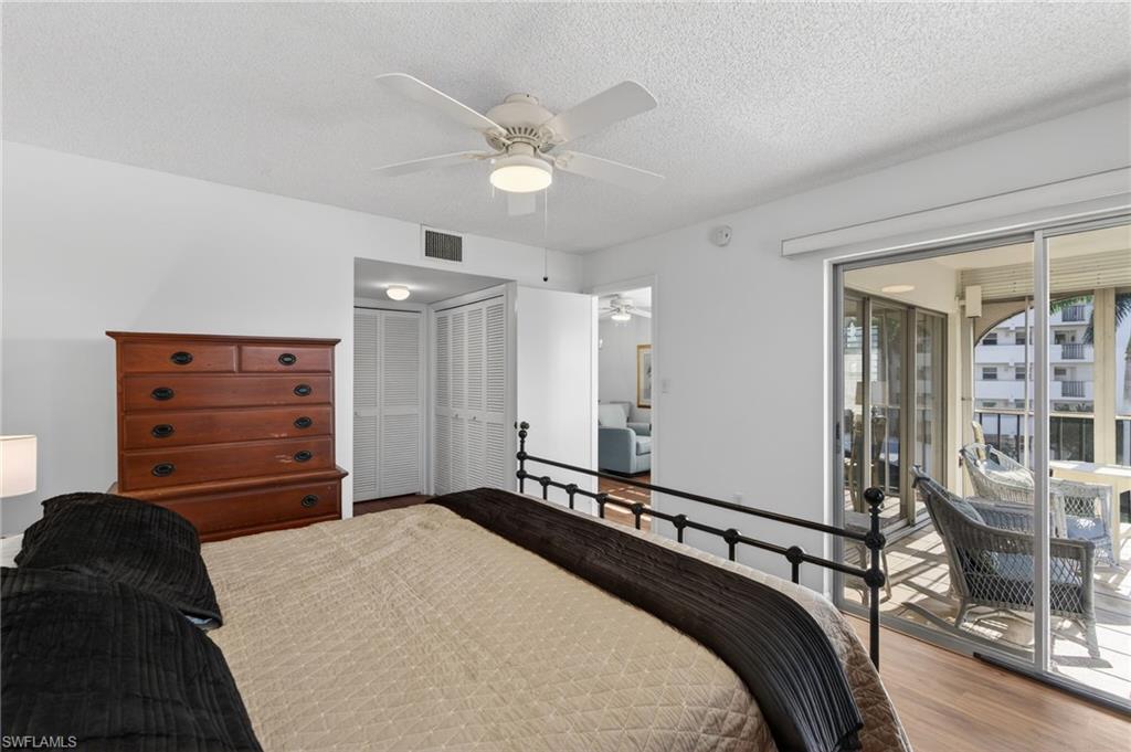 Bedroom featuring access to exterior, wood finished floors, two closets, ceiling fan, and a textured ceiling