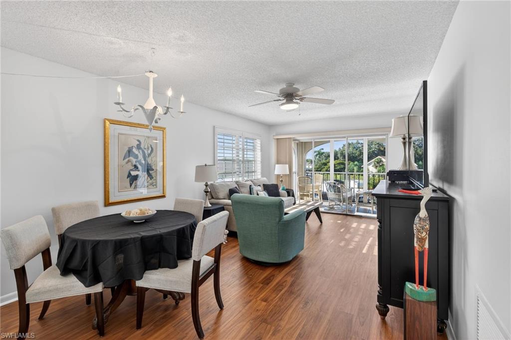 Dining area featuring wood finished floors, a chandelier, a textured ceiling, and ceiling fan