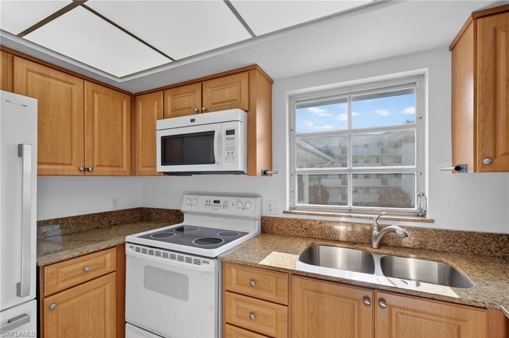 Kitchen with white appliances and light stone counters