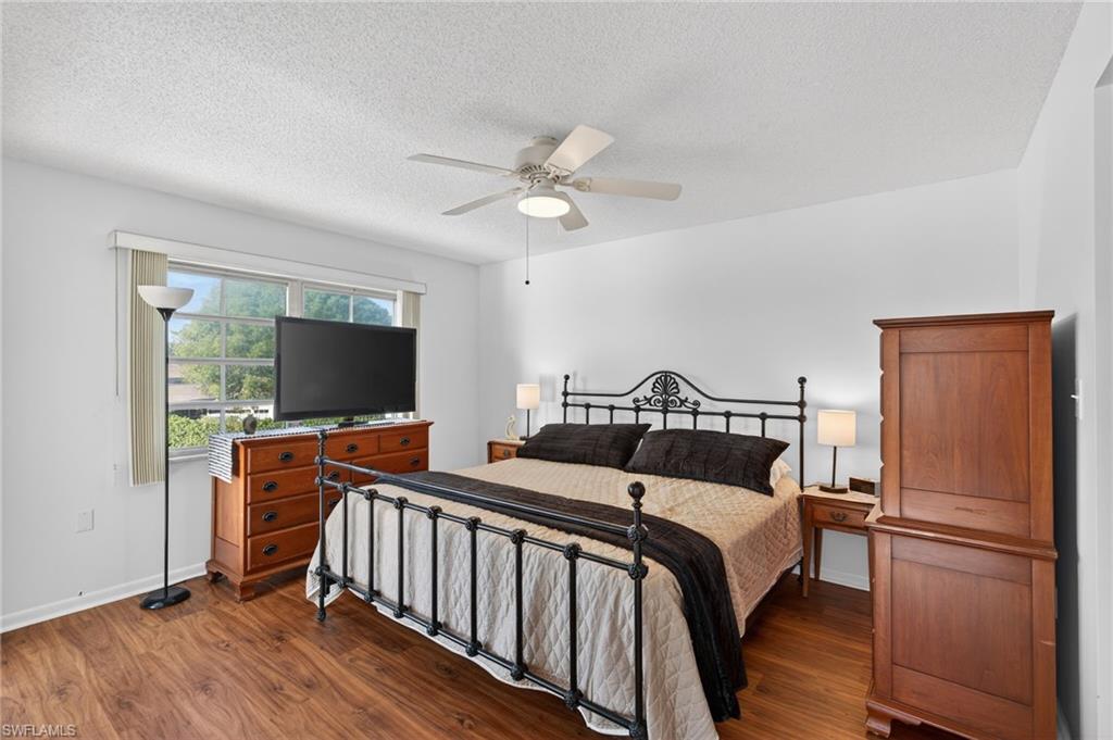 Bedroom featuring dark wood-type flooring, a ceiling fan, and a textured ceiling
