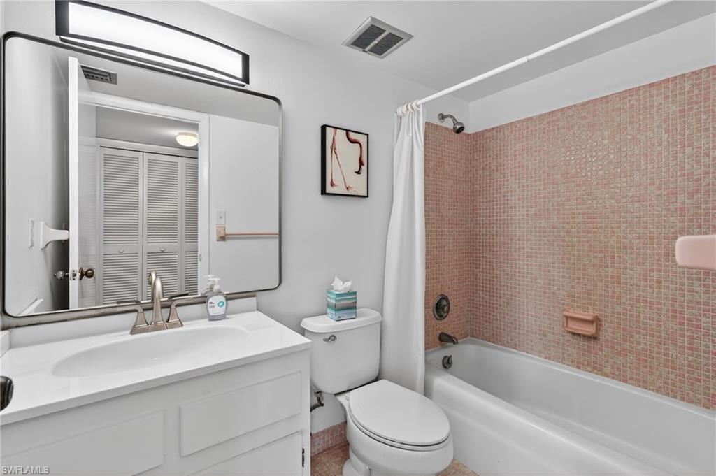 Bathroom with vanity, shower / tub combo with curtain, and a closet
