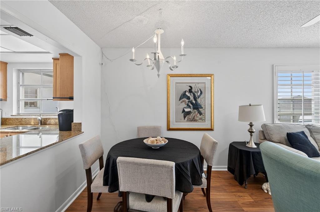 Dining room featuring dark wood-type flooring, a textured ceiling, and a chandelier