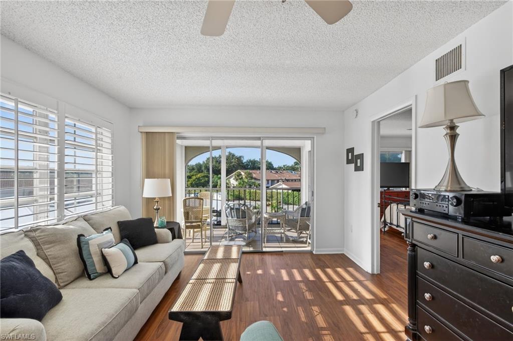 Living area featuring a textured ceiling, dark wood-style floors, ceiling fan, and a sunroom