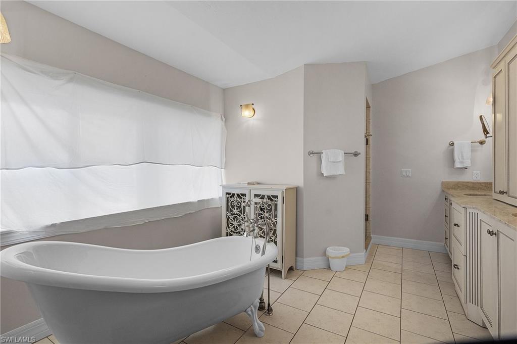 Bathroom featuring a freestanding tub, vanity, and light tile patterned flooring
