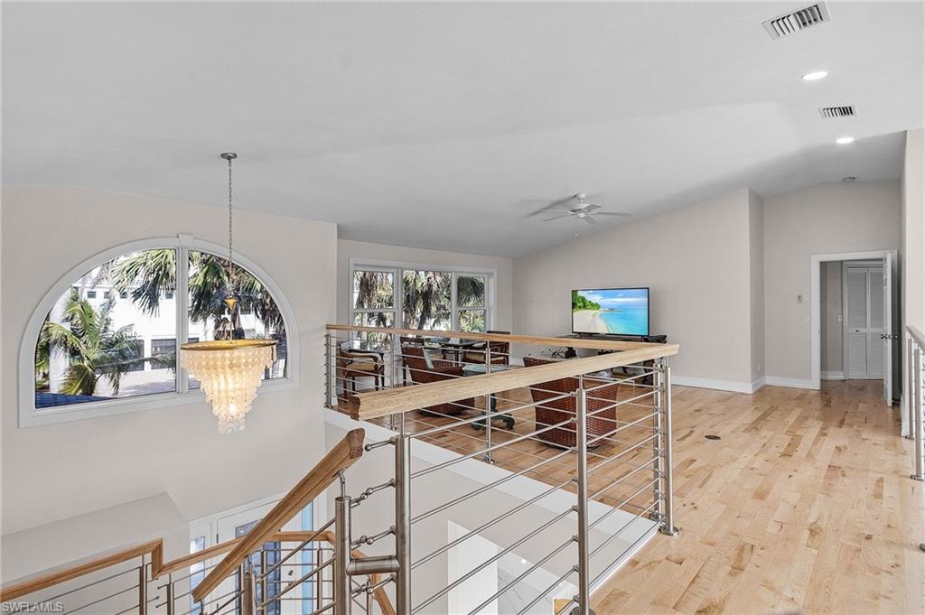 Hallway with an upstairs landing, vaulted ceiling, a chandelier, light wood-style flooring, and recessed lighting