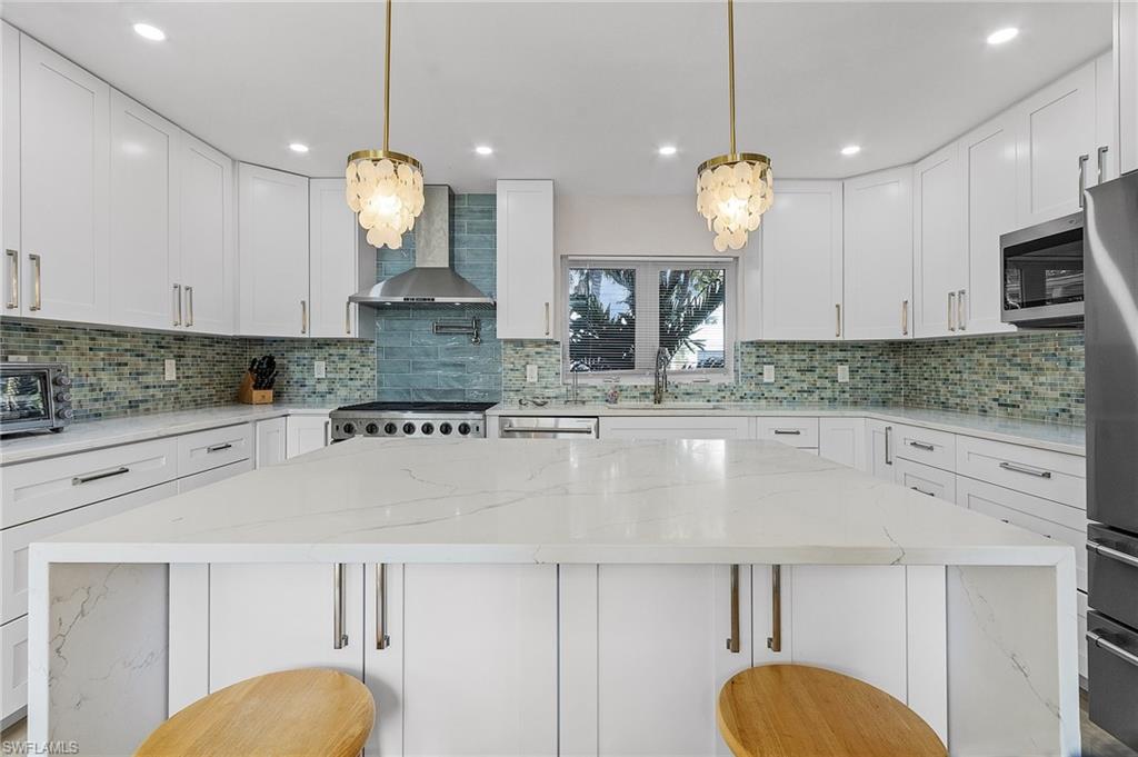 Kitchen featuring light stone counters, hanging light fixtures, white cabinets, and recessed lighting