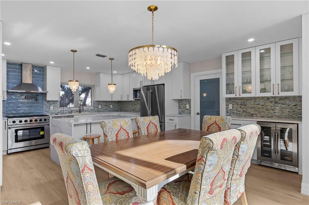 Dining room featuring wine cooler, a chandelier, light wood-style flooring, and recessed lighting