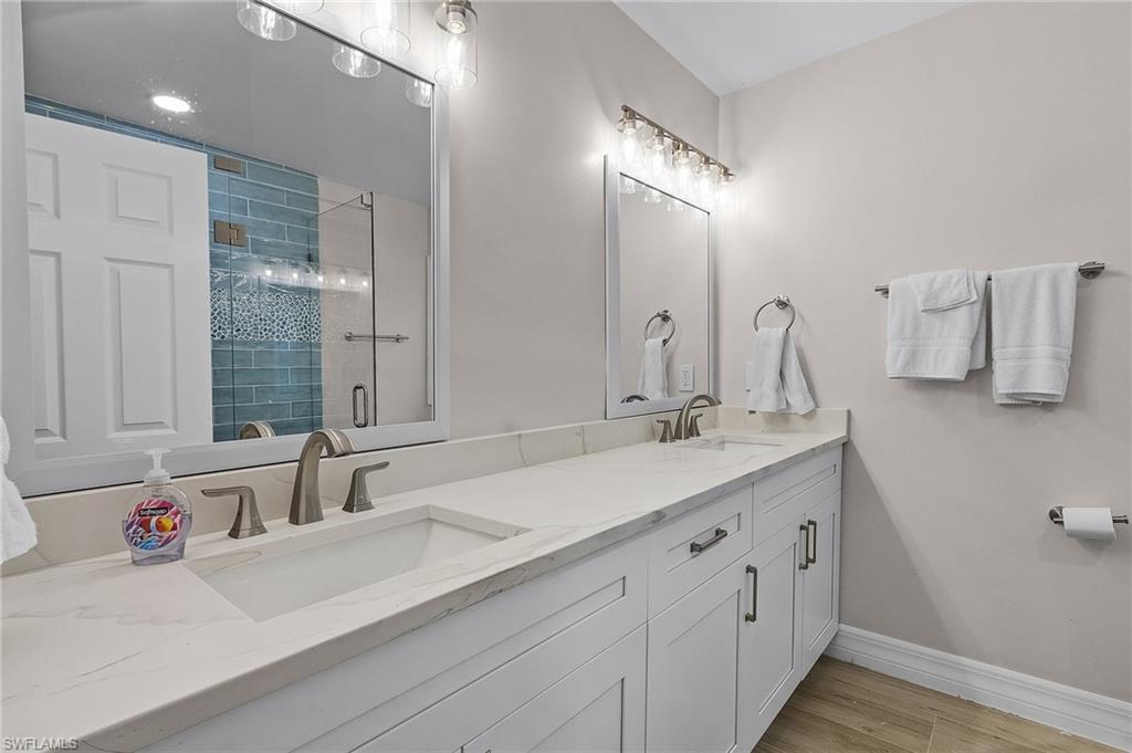 Bathroom with a stall shower, double vanity, and light wood-style floors