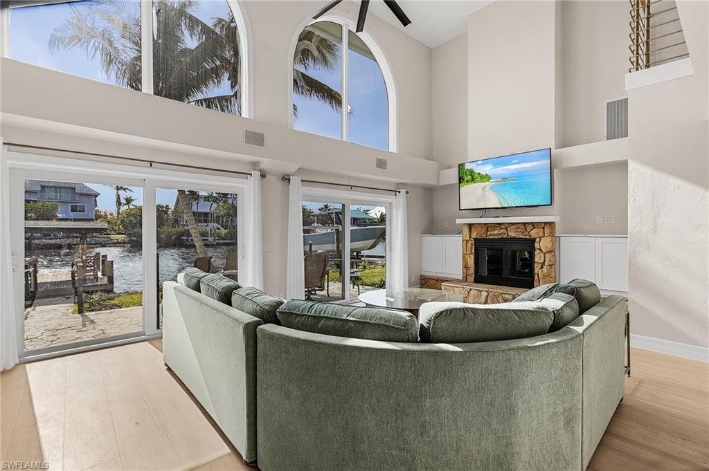 Living area featuring a stone fireplace, a high ceiling, and light wood-style flooring