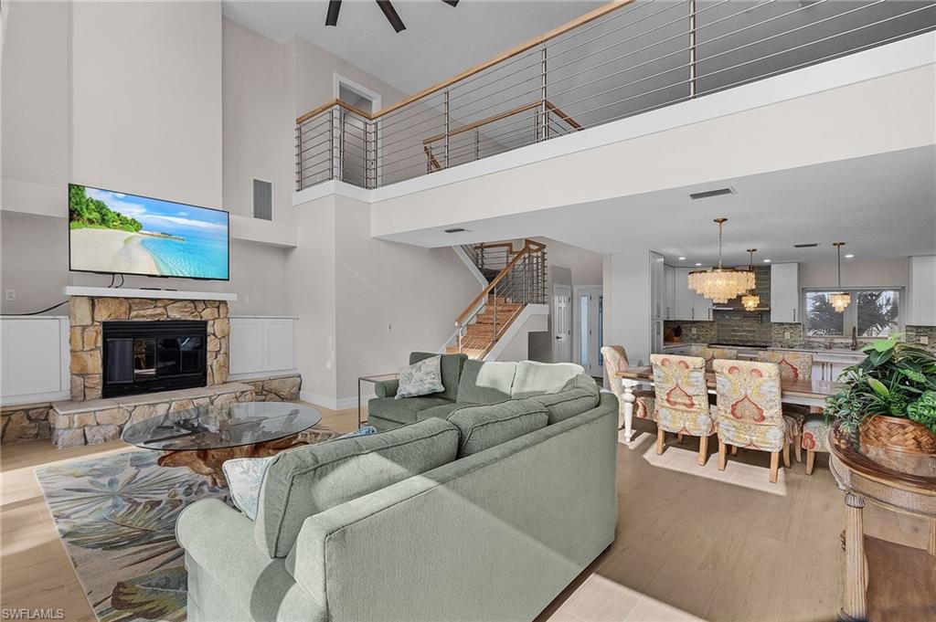 Living area with a fireplace, stairs, wood finished floors, and ceiling fan