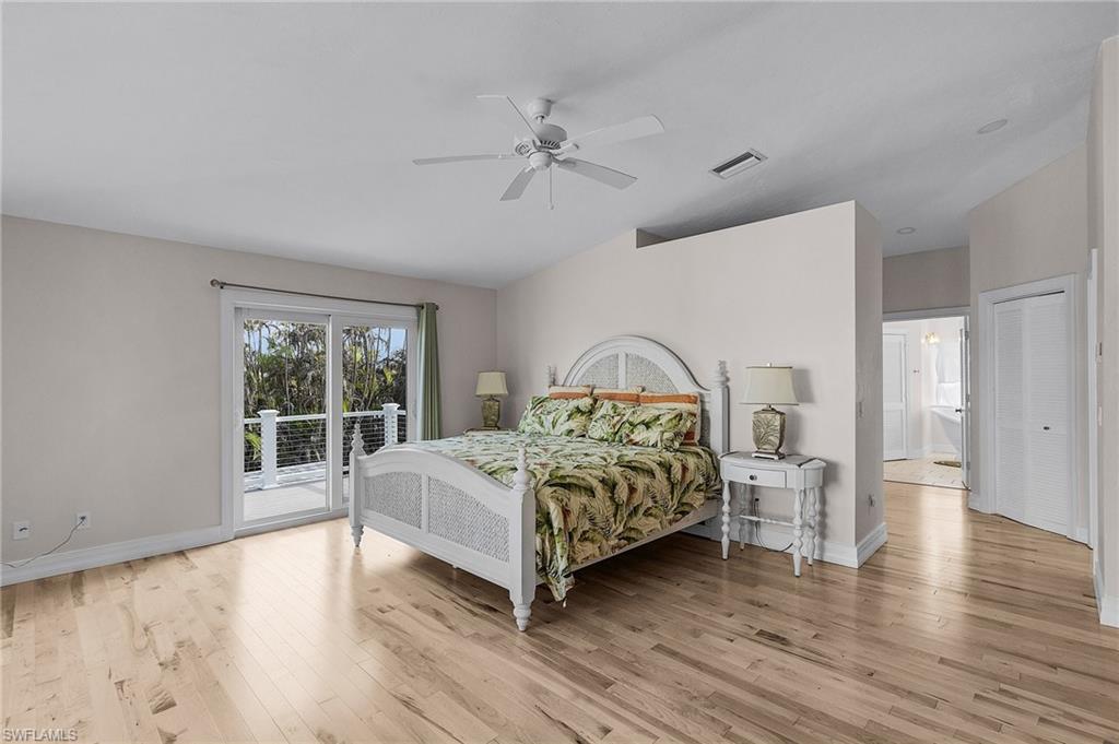 Bedroom with access to exterior, light wood-style flooring, a ceiling fan, and vaulted ceiling