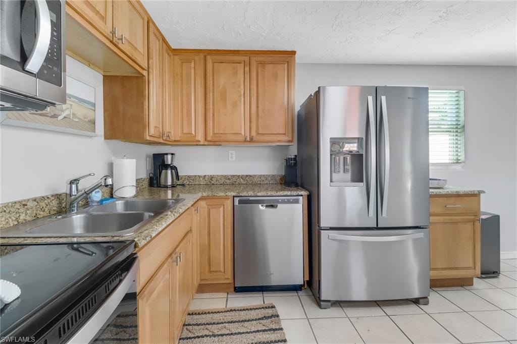 Kitchen with sink, stainless steel appliances, a textured ceiling, and light tile patterned floors