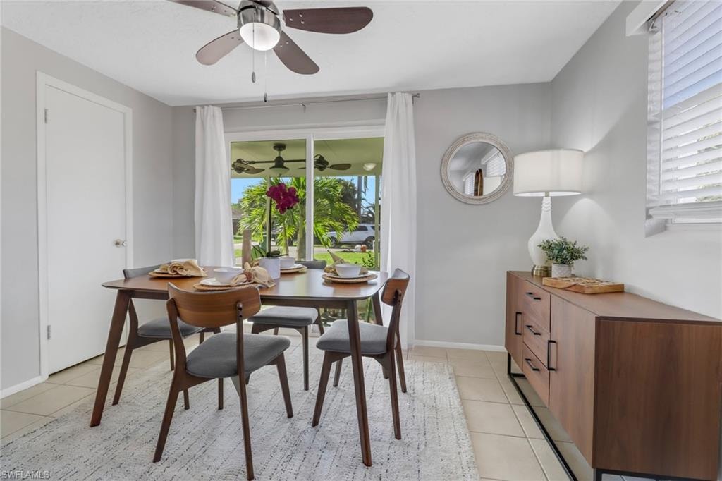 Tiled dining space with a healthy amount of sunlight and ceiling fan