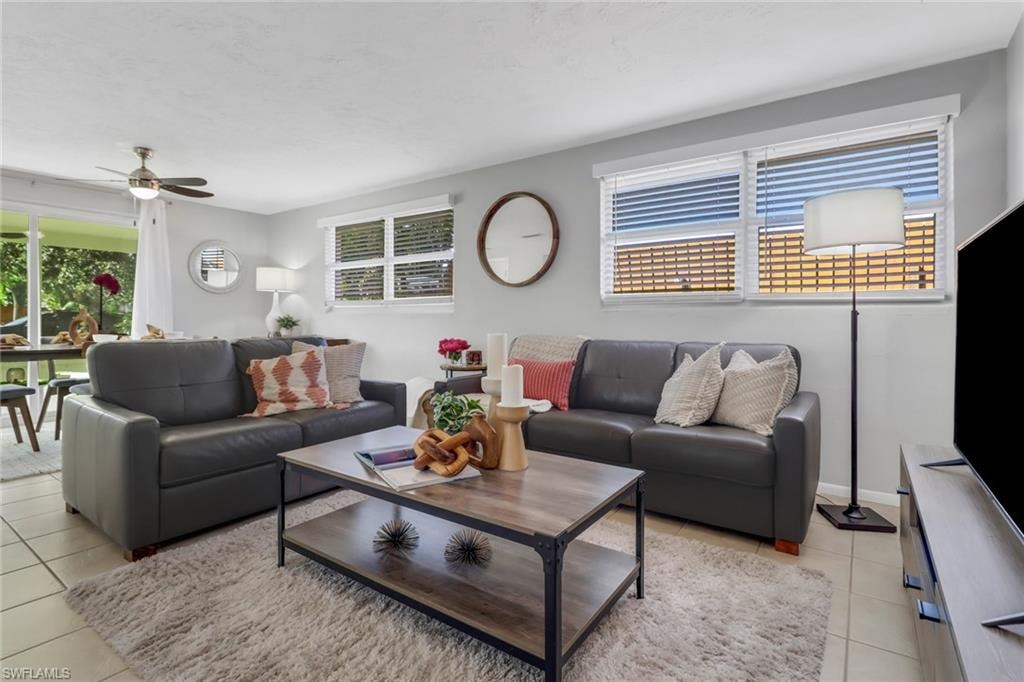 Tiled living room featuring ceiling fan and a wealth of natural light