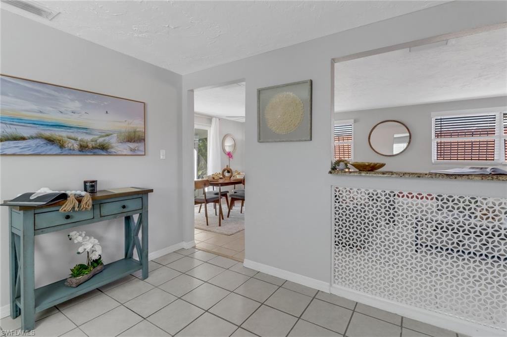 Hallway featuring a textured ceiling and light tile patterned floors