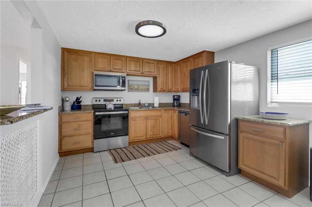 Kitchen featuring stainless steel appliances, light stone countertops, and sink