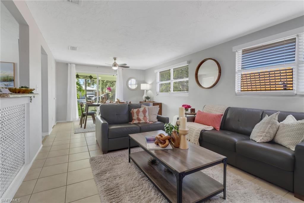 Living room featuring light tile patterned flooring, a textured ceiling, and ceiling fan