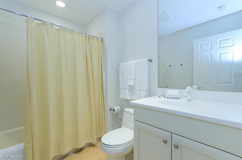 Bathroom featuring vanity, shower / bath combo with shower curtain, and recessed lighting