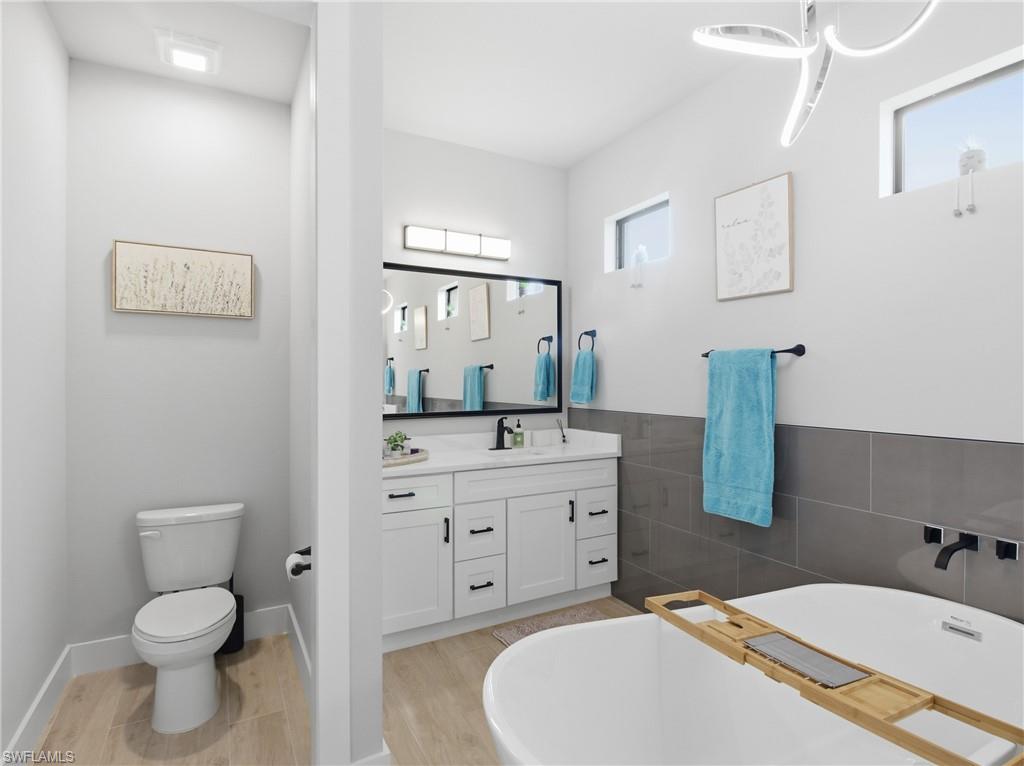Bathroom featuring a soaking tub, vanity, and tile walls