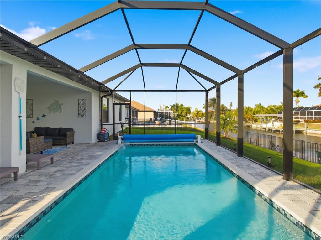 Outdoor pool with screened enclosure, a sunroom, a water view, outdoor lounge area, and a patio