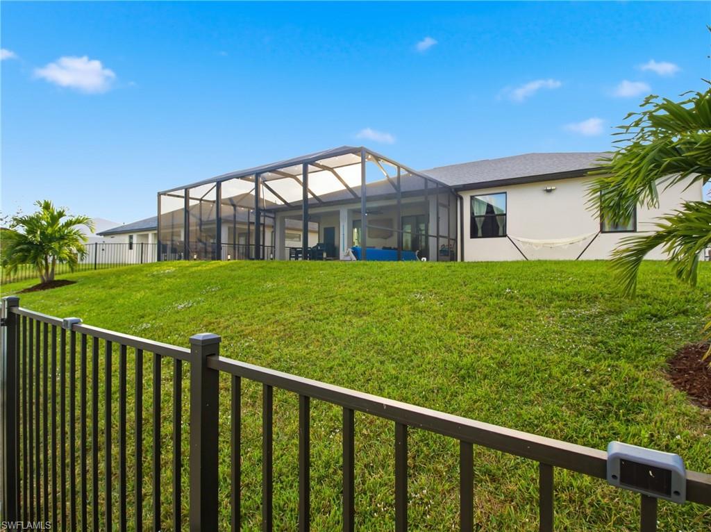 Back of house featuring glass enclosure, a sunroom, a fenced backyard, and stucco siding