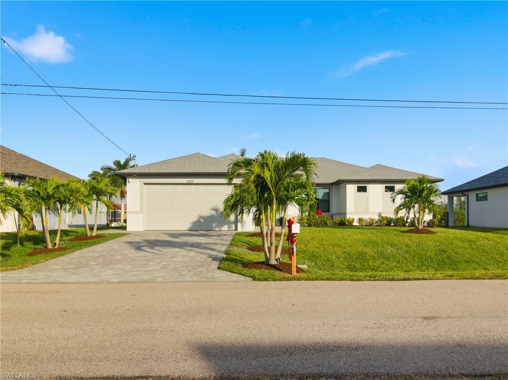 Single story home featuring decorative driveway, a front lawn, a garage, and stucco siding