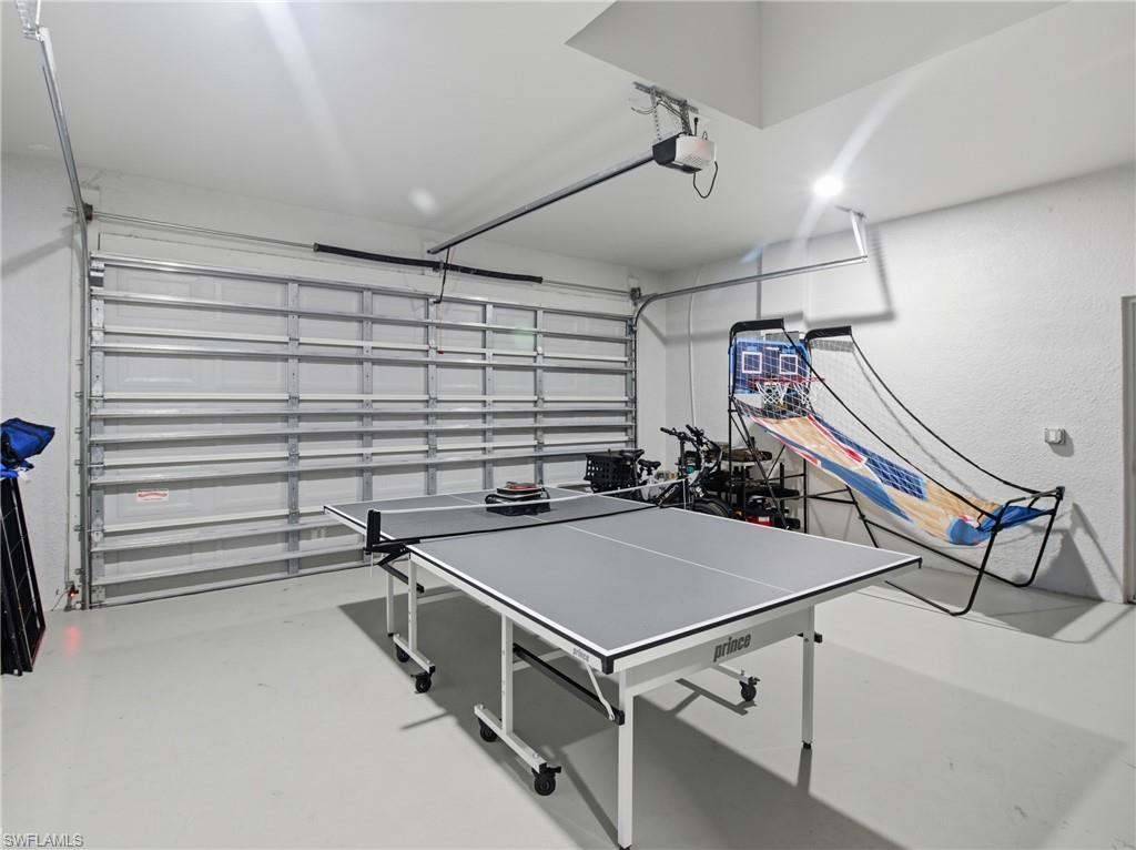 Recreation room featuring finished concrete flooring and a garage