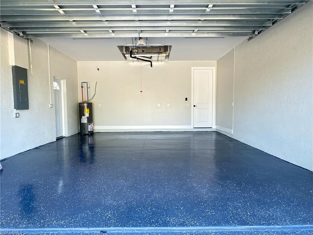 Garage with electric panel, a textured wall, and electric water heater