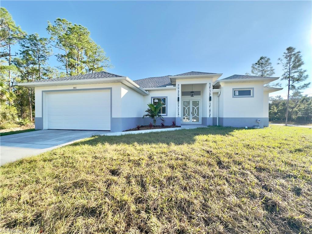 Prairie-style home featuring stucco siding, an attached garage, a front lawn, driveway, and french doors
