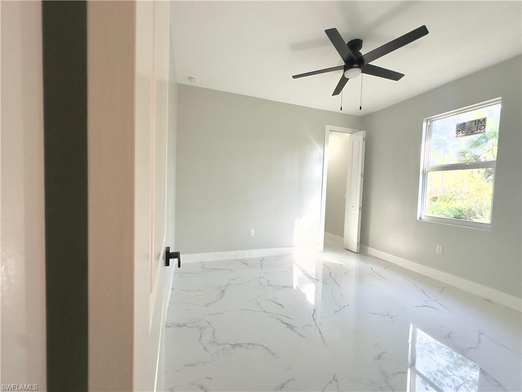 Spare room with light marble finish floors and ceiling fan
