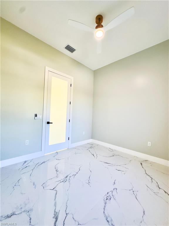 Unfurnished room featuring marble finish floors and ceiling fan