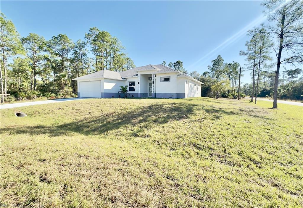 Ranch-style home with stucco siding, a front lawn, a garage, and driveway