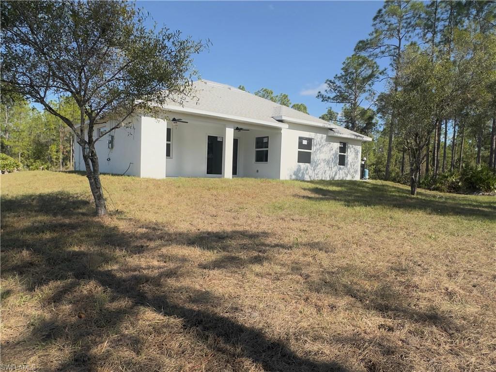 Back of property featuring ceiling fan, stucco siding, a yard, and a patio area