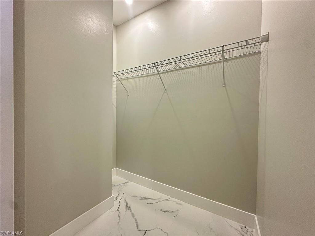 Walk in closet featuring marble finish flooring